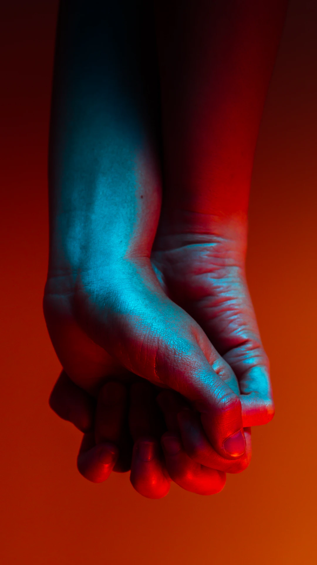 two person holding hands near orange background