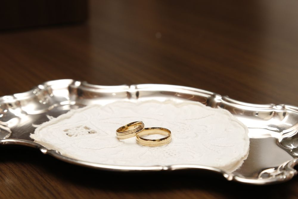 Close-up of gold wedding rings on a decorative silver tray, perfect for elegant celebrations.