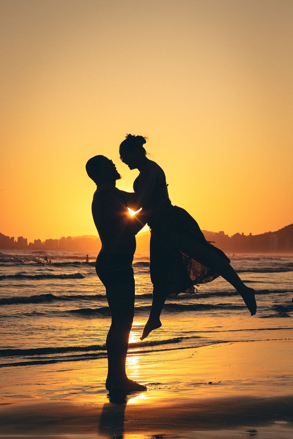 Silhouette of a couple embracing on a beach during a breathtaking sunset.