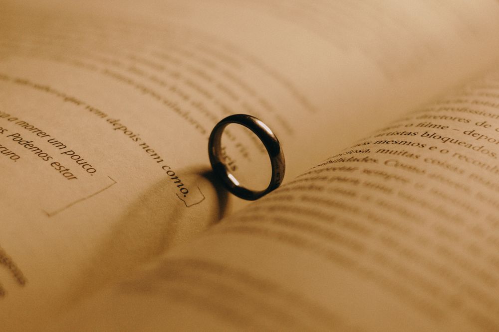 Engagement ring casting heart-shaped shadow on book page, symbolizing love.