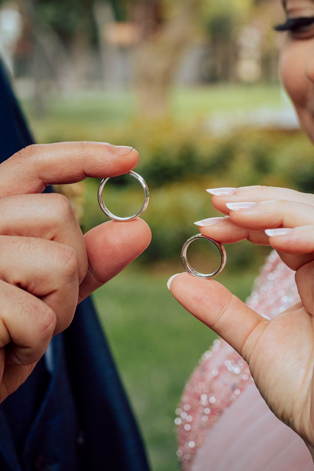Close-up of couple exchanging rings outdoors, symbolizing unity and love.