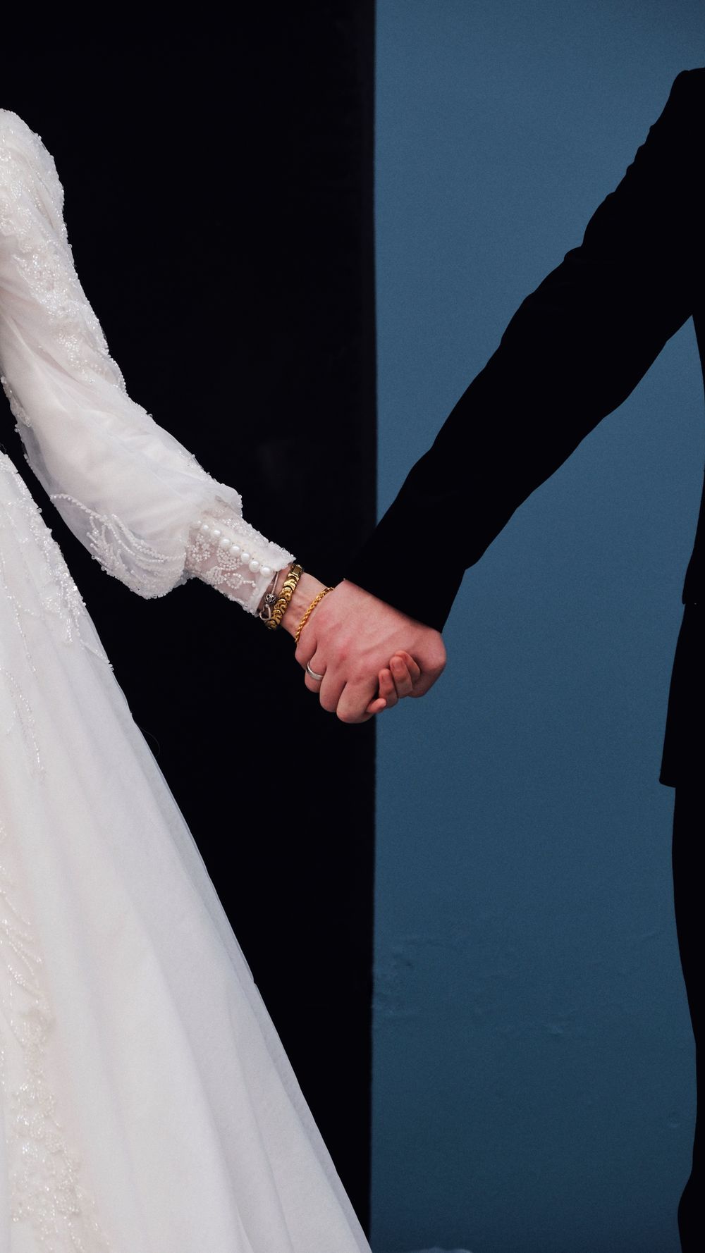 Close-up of a bride and groom holding hands, showcasing elegant wedding attire.