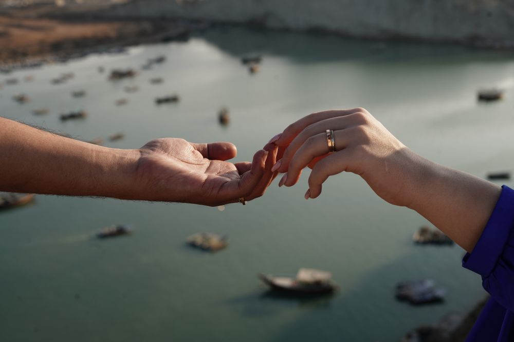Two hands reaching towards each other above a serene water landscape, symbolizing connection and togetherness.