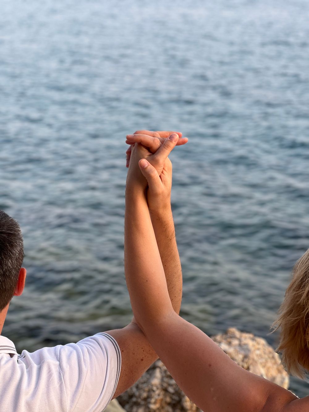 A couple's hands intertwined by the serene Adriatic Sea in Croatia, symbolizing unity and love.