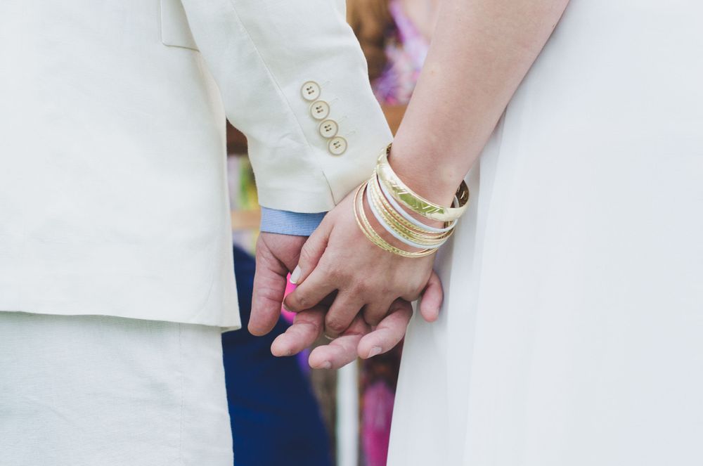 Close-up of bride and groom holding hands, symbolizing love and unity at a wedding.