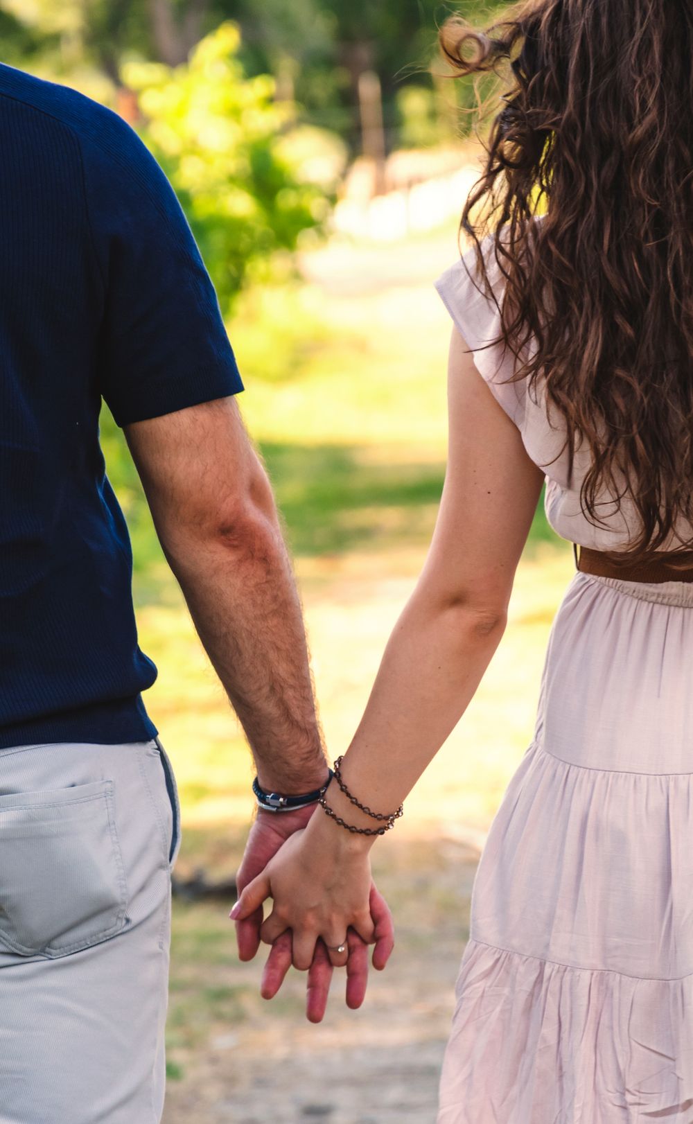 A couple holding hands in a sunny park, symbolizing love and connection.