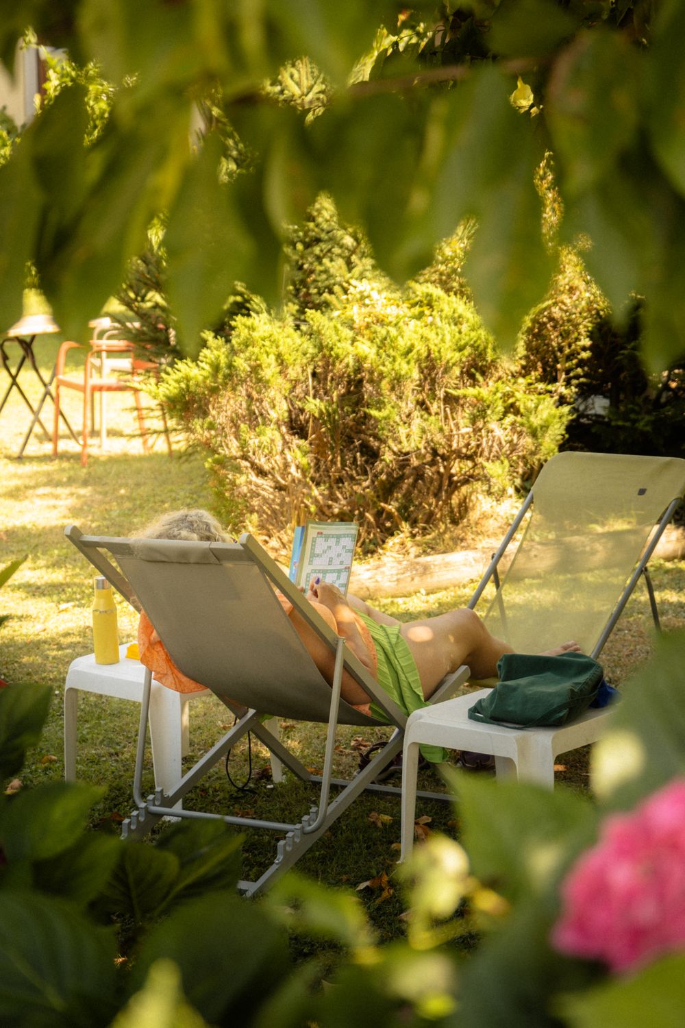 Person relaxing on a hammock in a lush garden on a sunny day.