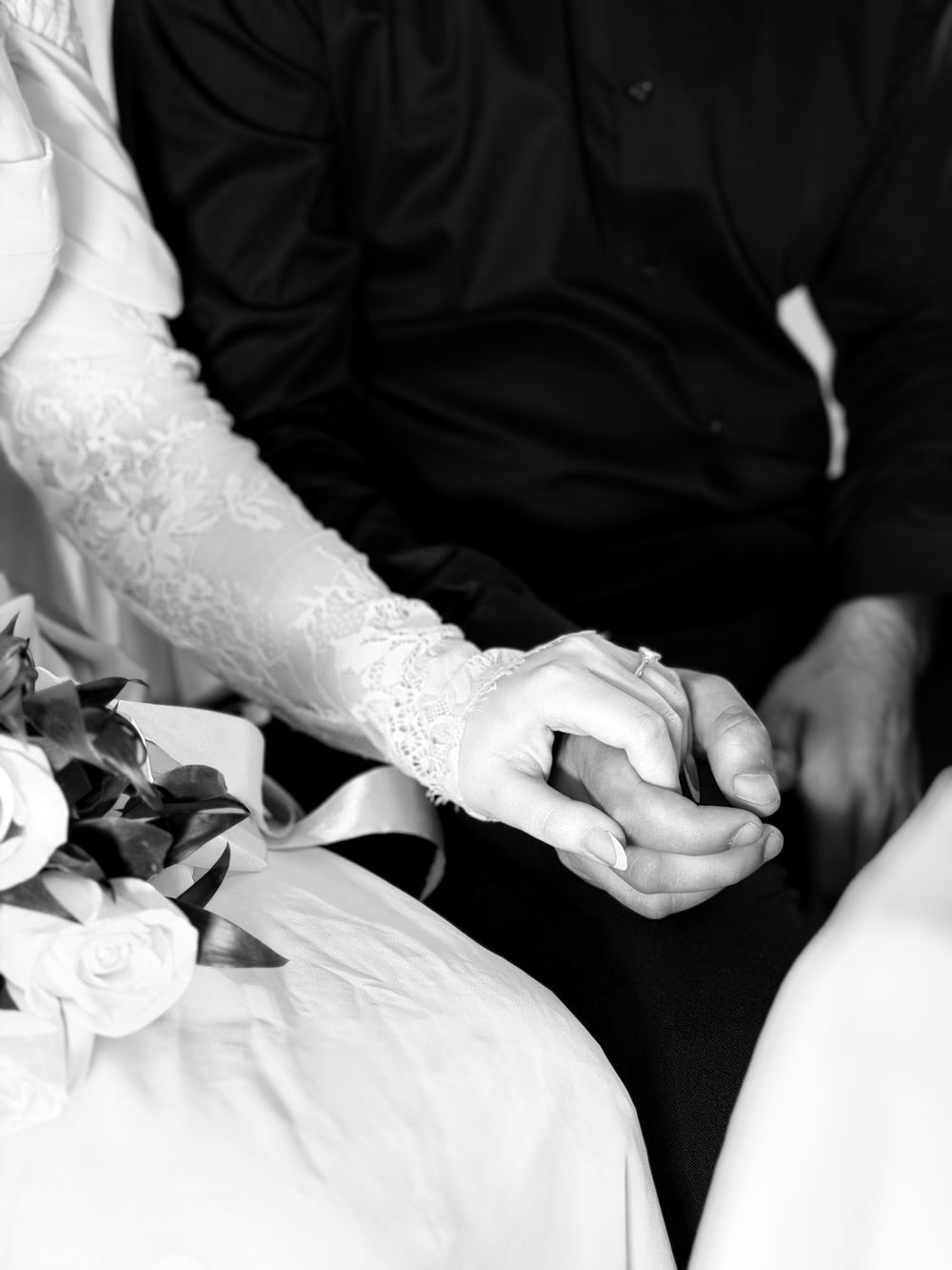 Close-up of a couple holding hands, capturing an intimate and timeless wedding moment in black and white.