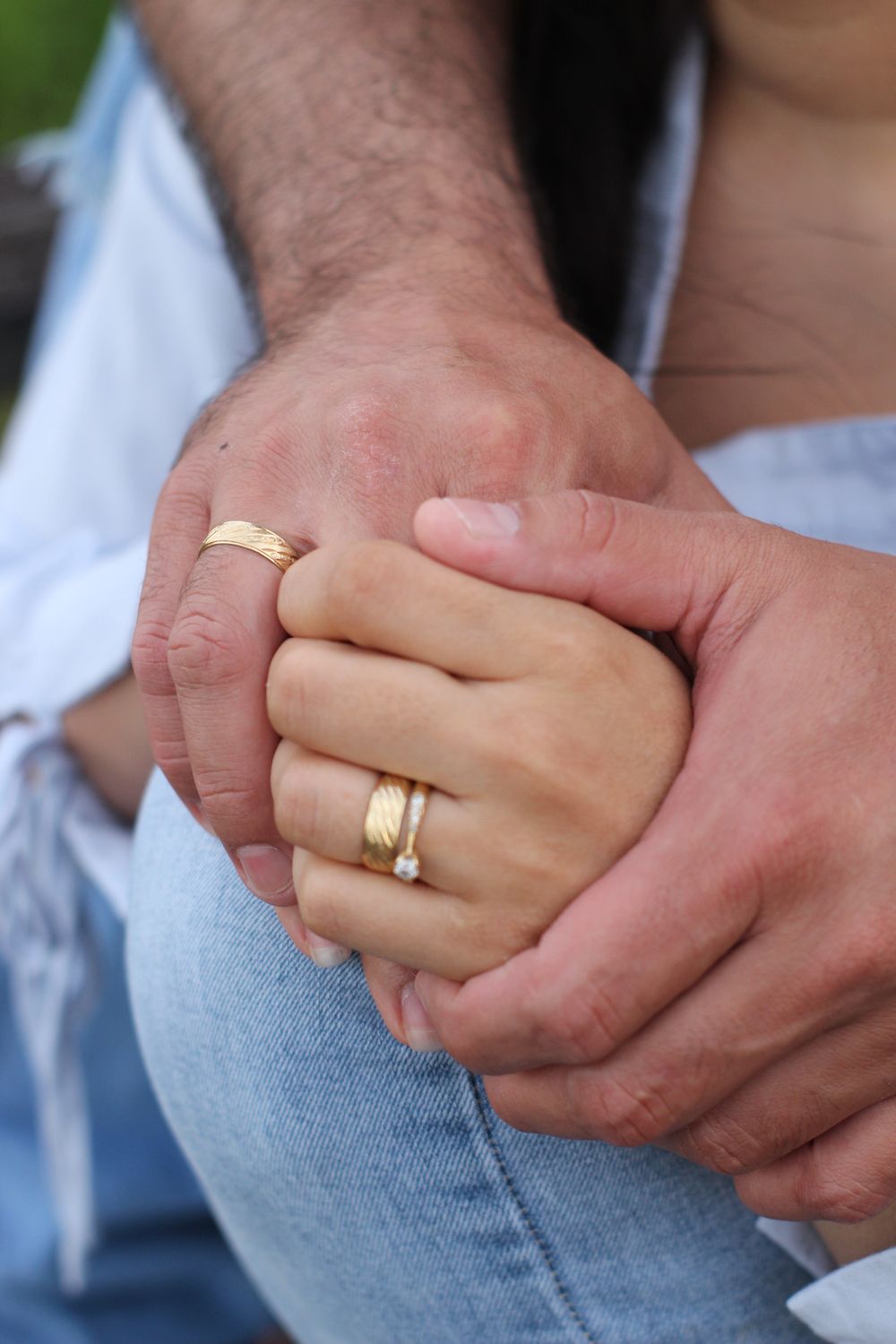 Close-up of a couple's hands with wedding and engagement rings, symbolizing love and commitment.