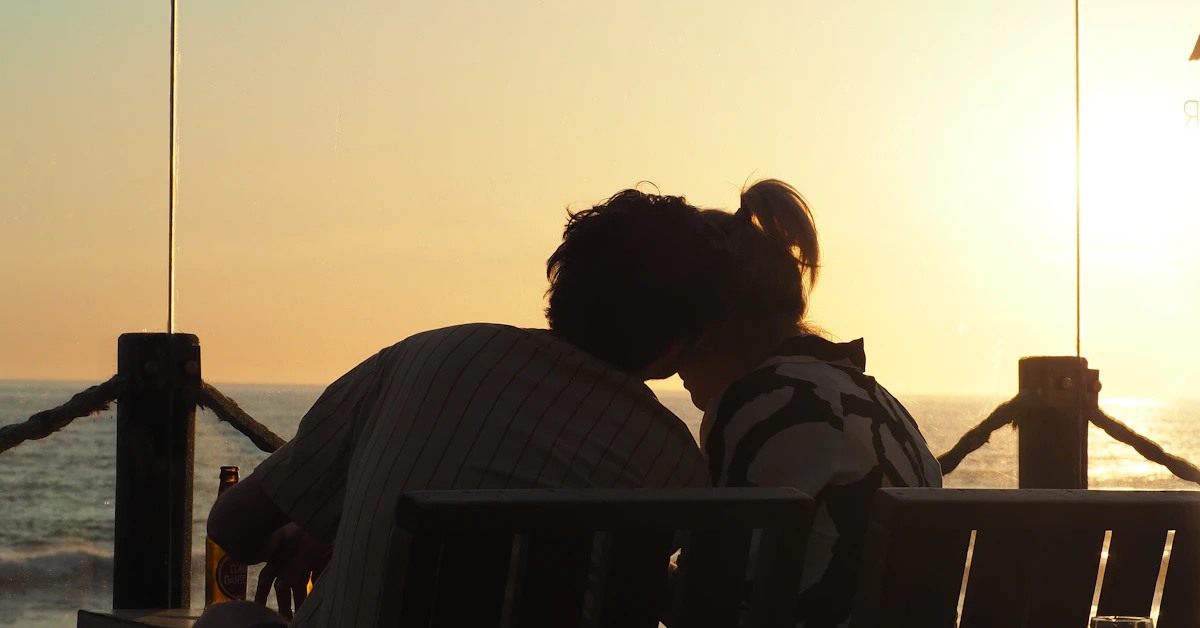a man and a woman sitting on a bench in front of the ocean